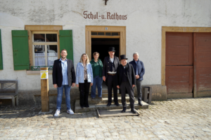 Bild vergr&ouml;&szlig;ern: Das Schul- und Rathaus steht in diesem Jahr im Mittelpunkt des Museumsprogramms. Die Vorfreude auf die neue Museumssaison ist gro&szlig;.
(von links: Amtsleiter Nils Bambusch, B&uuml;rgermeisterin Marina Jung, Museumsleiterin Vera Jovic-Burger, Dorfschulmeister Lothar Schellhorn und Erwin Ulmer, Landrat Stefan B&auml;r)